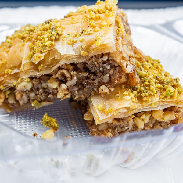 Two pieces of baklava, a Greek dessert, with flaky pastry, nuts, and a pistachio topping.
