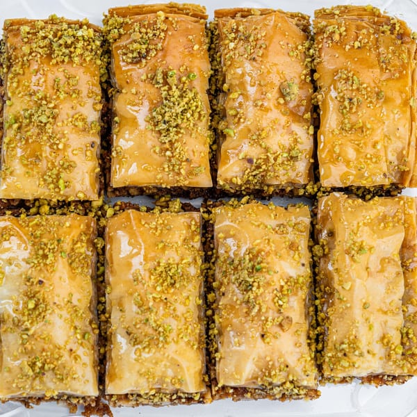 Eight pieces of golden-brown baklava, drizzled with honey and sprinkled with chopped pistachios.